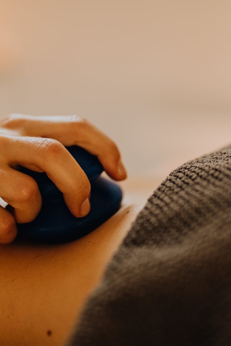 Hands applying relaxing massage therapy with hot stones in a calming spa environment.